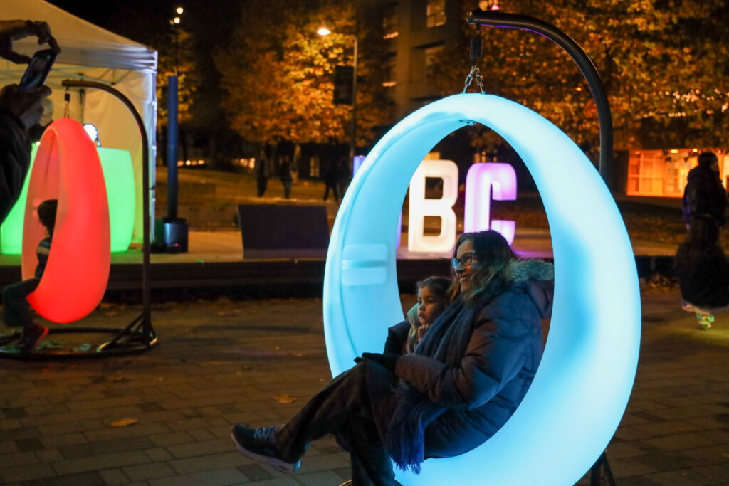 Child and caregiver on LED swing at Light Up Lee Square Event